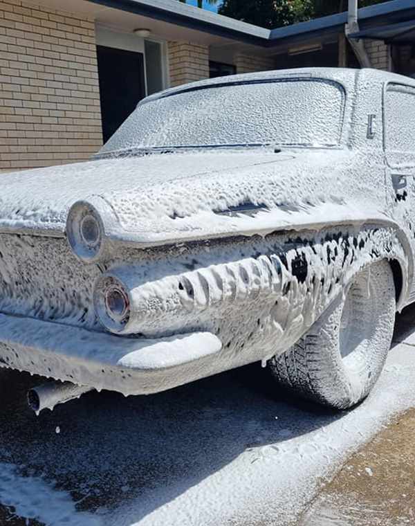 Classic car covered in foam for exterior clean
